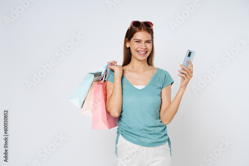 Young woman holding shopping bags while using mobile phone isolated over white background.
