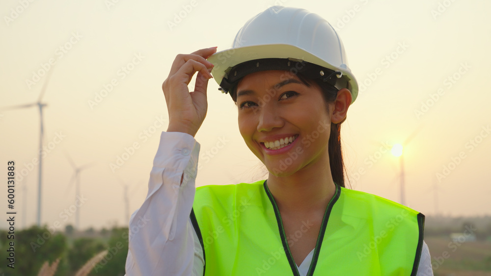 Portrait of female enginees looking to camera with smiling at wind turbine farm. Portrait of female enginees looking to camera with smiling at wind turbine farm.