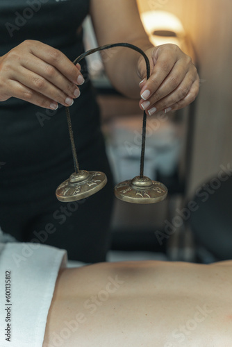 Sound massage, treatment with Tibetan bowls in the spa salon. Female meditation during traditional Nepalese practices using the vibration of bronze bowls for energy recovery