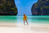Beautiful young blonde woman in orange dress on a Maya Bay Beach during excursion of phi phi leh island in andaman sea thailand.
