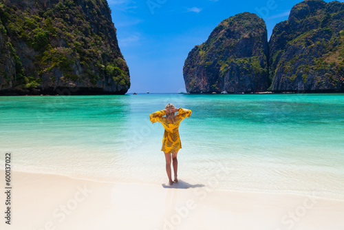 Beautiful young blonde woman in orange dress on a Maya Bay Beach during excursion of phi phi leh island in andaman sea thailand. photo