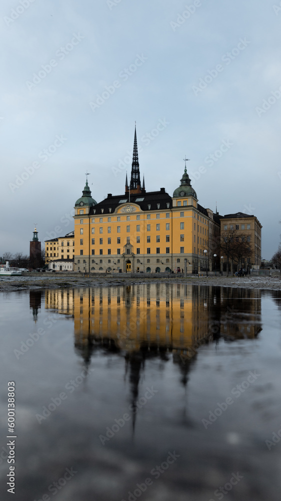 Yellow caste and cloudy blue sky reflecting in water puddle on street Sweden Stockholm