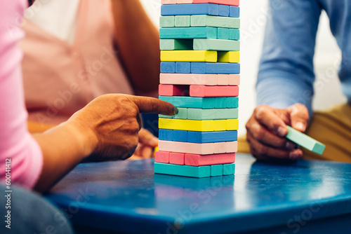 Senior people playing a wooden block tower, risk and strategy of project management. Concept of business risk with domino blocks. Older People playing jenga block removal game on table at home photo