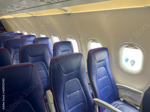 inside airplane many blue seats in row empty no people and aircraft ceiling with air conditioner buttons no smoking sign.travel trip concept, journey