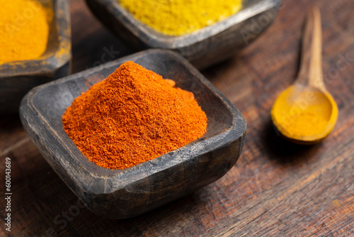 Turmeric, pepper and curry powder in container on wooden background