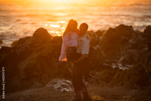 A young couple having fun on the ocean during a golden sunset. .