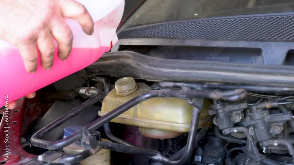 Pouring coolant, Service of cars. Pouring antifreeze. Mechanic fills the coolant G12 to tank in