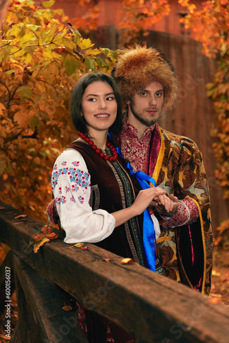 Young couple dressed traditional ukrainian clothing. Serious cossack man and smiling woman in embroidered costumes outdoors. Vintage outfit.