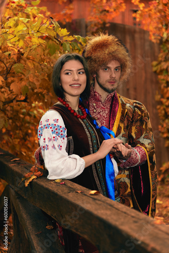 Obraz na płótnie Young couple dressed traditional ukrainian clothing. Serious cossack man and smiling woman in embroidered costumes outdoors. Vintage outfit. w salonie