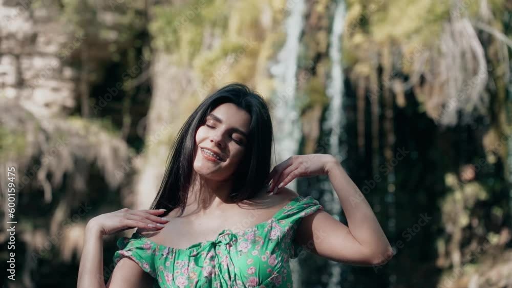 Beautiful model in a turquoise dress posing near a mountain waterfall.Wildlife concept Beautiful model in a turquoise dress posing near a mountain waterfall.Wildlife concept