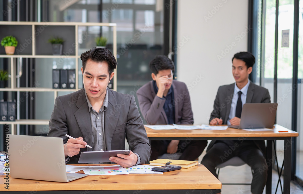 Obraz premium Asian business team consists of marketing staff. accountant and financial officer Help each other analyze company profits using tablets. calculator Laptop computers, graph paper, and corporate pens.