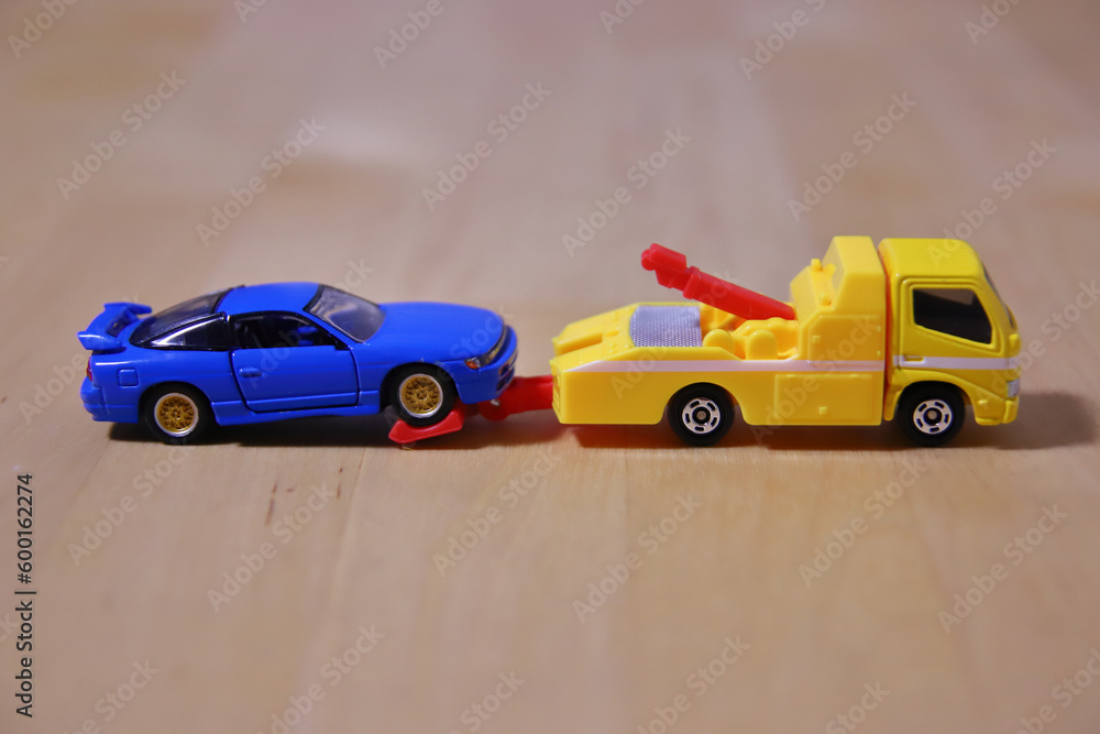 Fototapeta premium レッカーされる青いミニカー