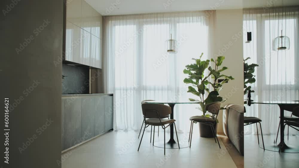 Dolly shot of cozy modern kitchen the table and chairs are by the window, white tulle is on the window. Interior supplemented with plants, slow motion shot. Dolly shot of cozy modern kitchen the table and chairs are by the window, white tulle is on the window. Interior supplemented with plants, slow motion shot.