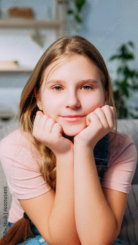 Smiling child. Kid portrait. Positive emotions. Satisfied pleased blond little girl with happy face expression in home interior looking at camera holding chin. Smiling child. Kid portrait. Positive emotions. Satisfied pleased blond little girl with happy face expression in home interior looking at camera holding chin.