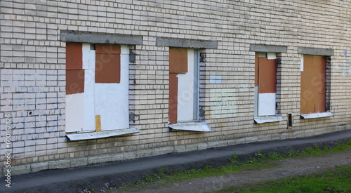Four boarded-up windows in a white brick wall