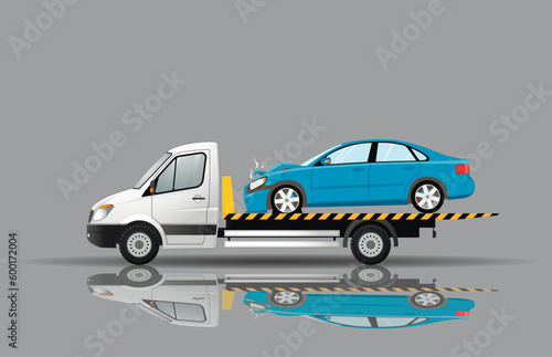 A tow truck transports a broken car after an accident. Reflection on the ground.