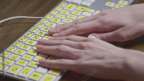 Close-up of a computer keyboard with braille. A blind girl is typing words on the buttons with her hands. Technological device for visually impaired people