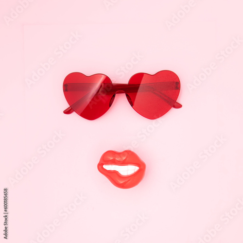 Red heart shape sunglasses and beautiful girl's mouth, attractive face idea, summer vacation mood, pastel pink background.