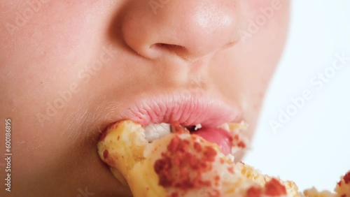 A close-up view of a child happily eating a donut. A child eats a doughnut. Fast food and unhealthy food. 4K resolution video