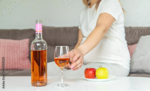 A pregnant woman drinks wine in a glass. Selective focus.