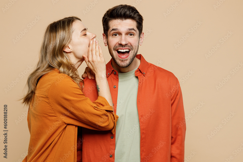Young couple two friend family man woman wear casual clothes whisper gossip and tell secret behind her hand sharing news together isolated on pastel plain light beige color background studio portrait - obrazy, fototapety, plakaty 