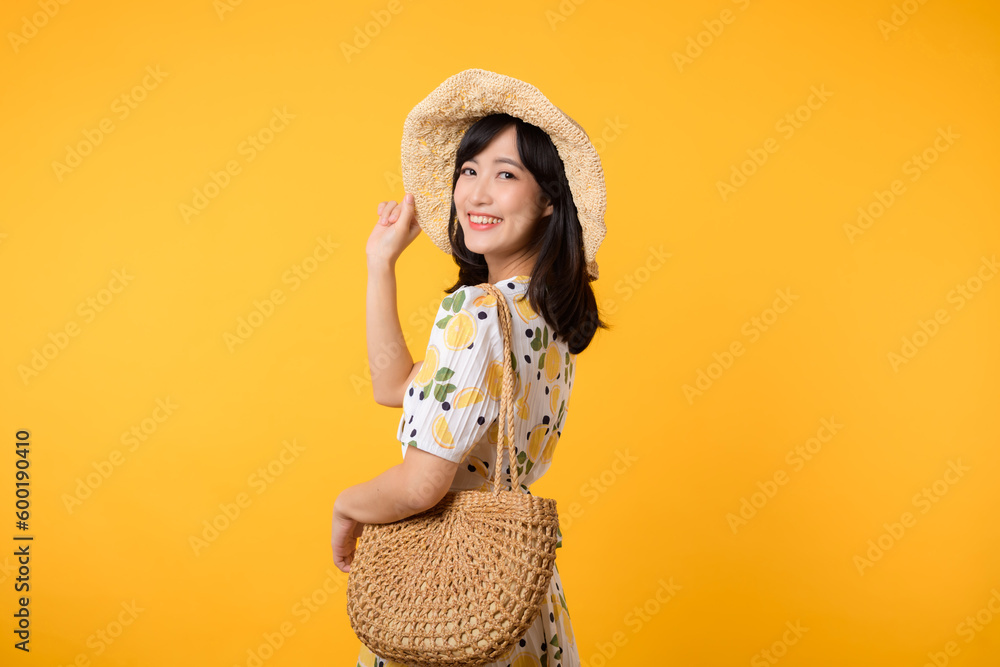 Portrait happy attractive young asian woman with trendy springtime dress, hat, sunglasses fashion and woven bag isolated on yellow background. Summertime sale shopping concept. - obrazy, fototapety, plakaty 