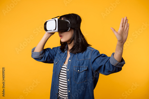 Young asian woman happy success wearing virtual reality headset game entertainment isolated on yellow background. Winner of cyber future video game concept.