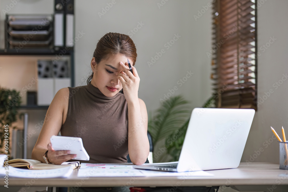 Fototapeta premium Serious female freelancer working online with accounting documents on modern laptop. Business woman busy working on laptop computer at office.