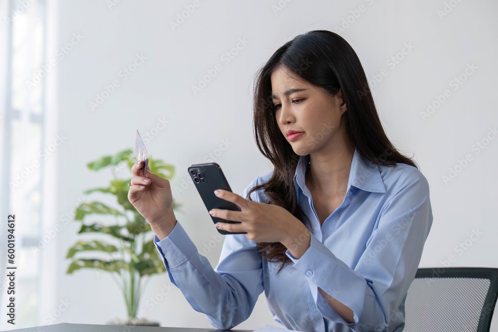Stressed Asian woman planning to pay loan and calculating credit card debt on the table Stressed Asian woman planning to pay loan and calculating credit card debt on the table