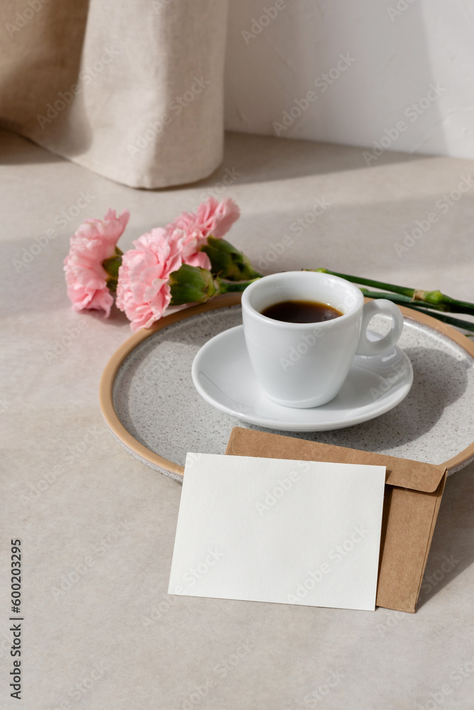 Empty paper card, coffe cup and flowers on beige background with sun light shadow, aesthetic floral holiday or wedding morning composition with mockup copy space Empty paper card, coffe cup and flowers on beige background with sun light shadow, aesthetic floral holiday or wedding morning composition with mockup copy space