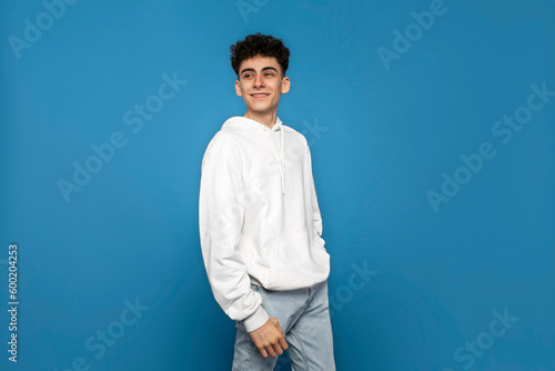 Quadro su tela Smiling youngster looking at the side, isolated blue background.