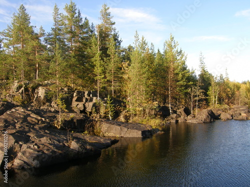 A rocky landscape with trees and rocks in the foreground. Suna River, Poor Porog Waterfall, Girvas, Republic of Karelia, Russia