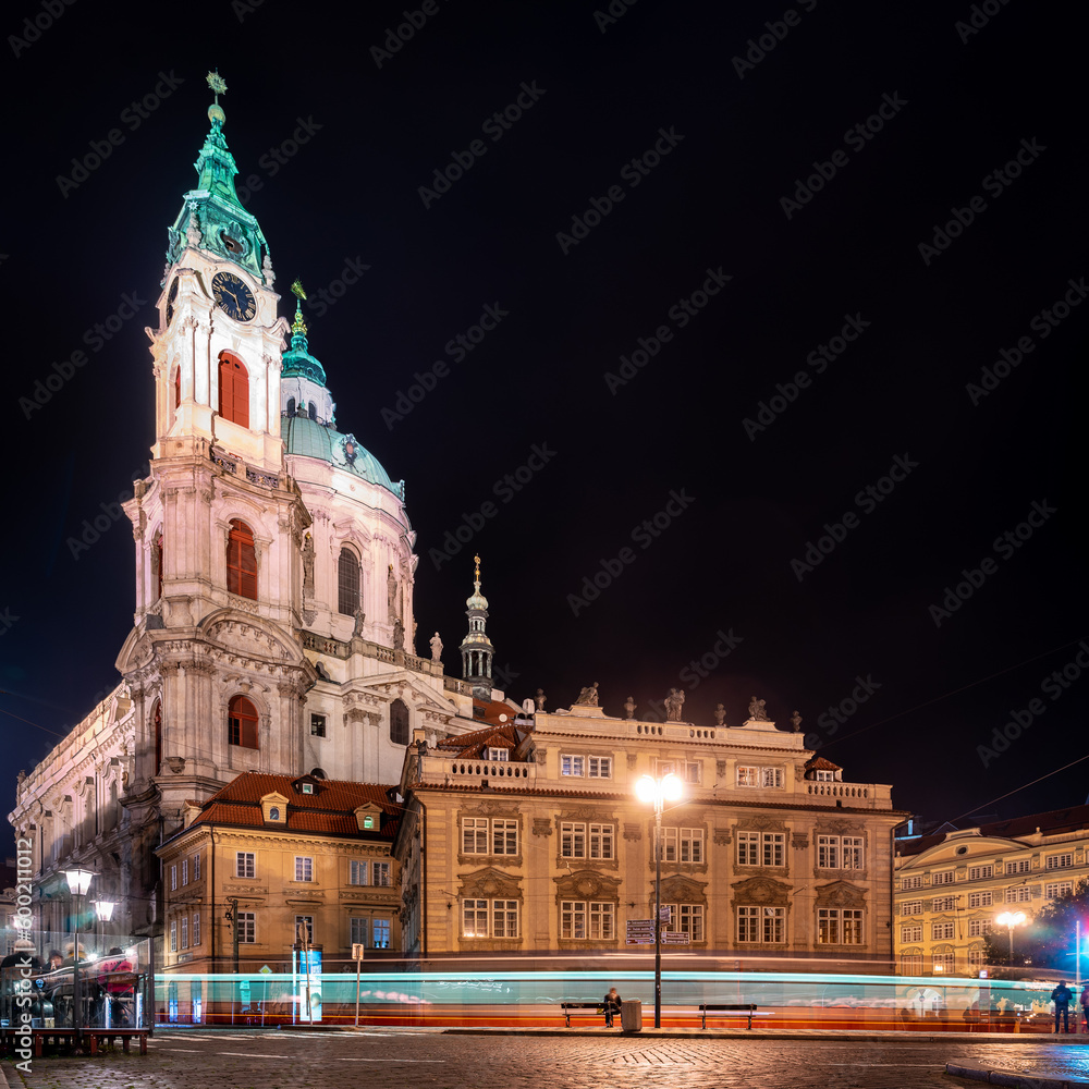 The Church of Saint Nicholas (Kostel svatého Mikuláše) in the Lesser Town of Prague at night with lighttrails of a passing tram.