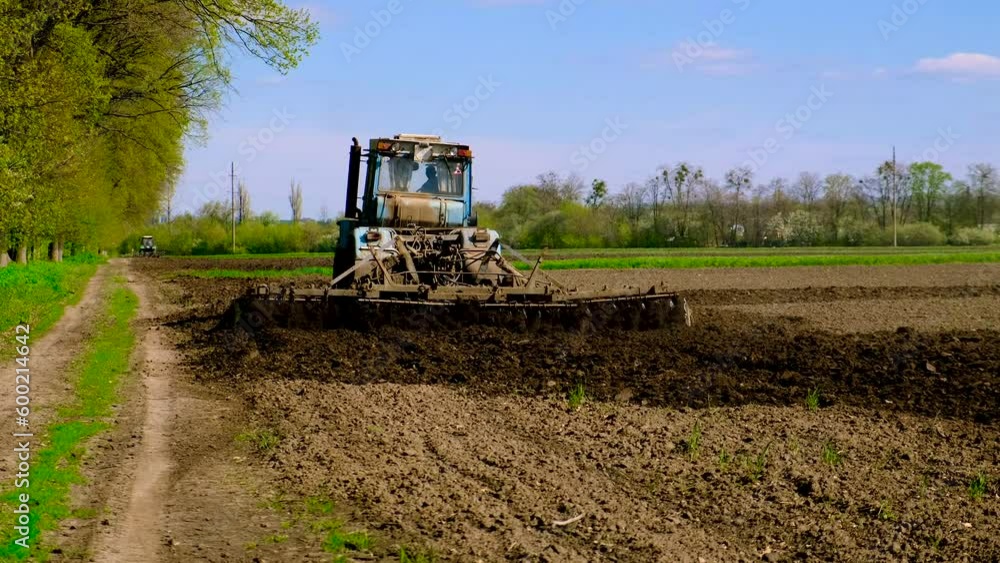 The tractor on the field cultivates the soil. Selective focus. The tractor on the field cultivates the soil. Selective focus.