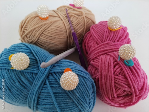 Colored balls of crochet thread, scissors and a needle on a white background