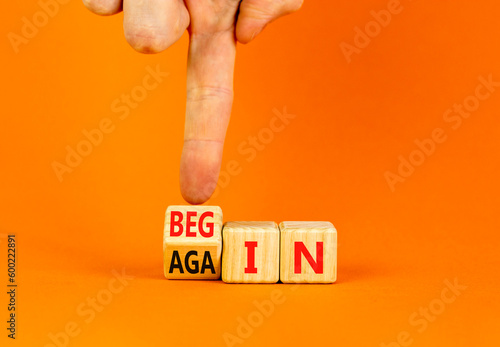 Begin again symbol. Businessman turns wooden cubes and changes the word begin to again. Beautiful orange table orange background. Business and begin again concept. Copy space.