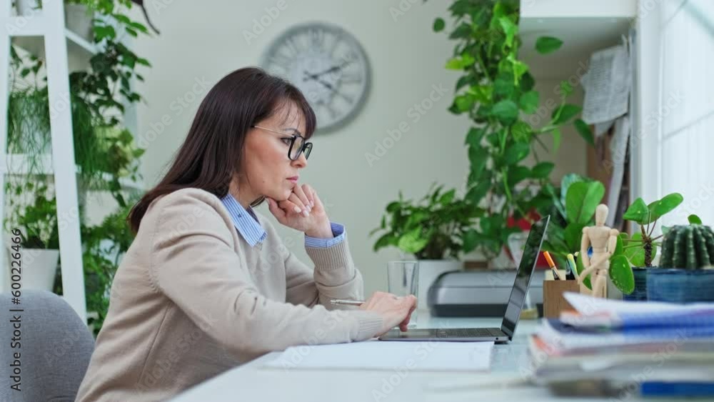 Profile view serious middle aged woman working in home office Profile view serious middle aged woman working in home office