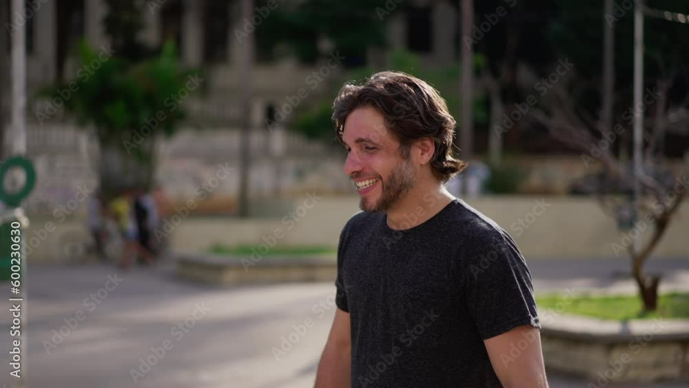 One happy handsome young man smiling and laughing while standing outside in city park. Authentic laugh and smile of a male caucasian person candid expression One happy handsome young man smiling and laughing while standing outside in city park. Authentic laugh and smile of a male caucasian person candid expression