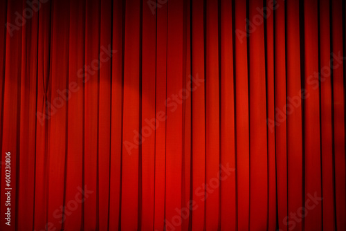 Theatrical stage curtain is bright red in the light of spotlights.