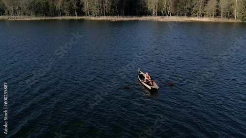 A lonely man oaring the boat at middle of lake.