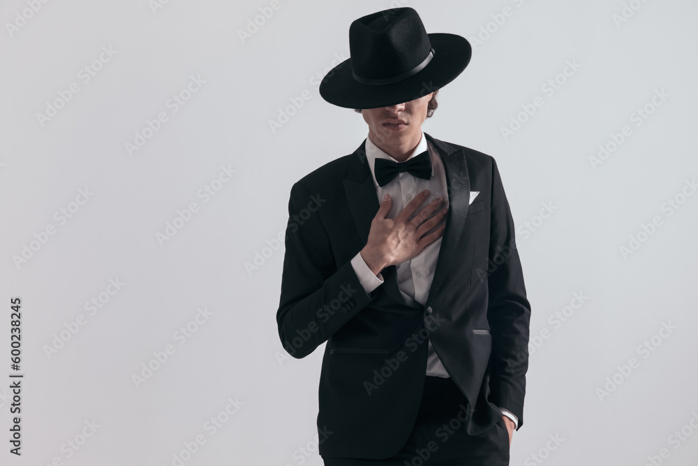 elegant young man in black tuxedo holding hand in pocket