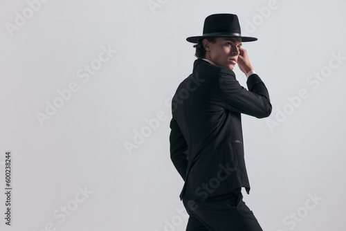 side view of sexy elegant man in tuxedo with hat looking to side
