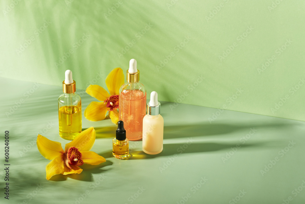 Φωτογραφία Cosmetic care products in glass bottles with orchid flowers - serums, cream, gel, oils