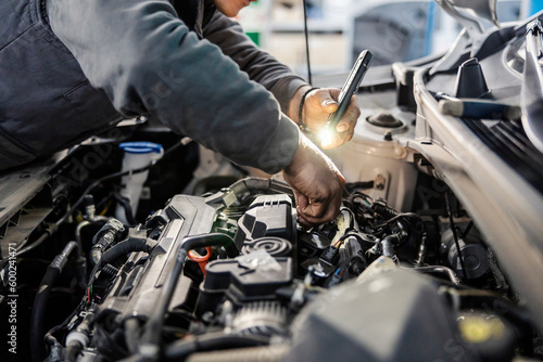 Fotografie, Tablou Mechanic's hands doing car checkup under the hood at the mechanic's shop
