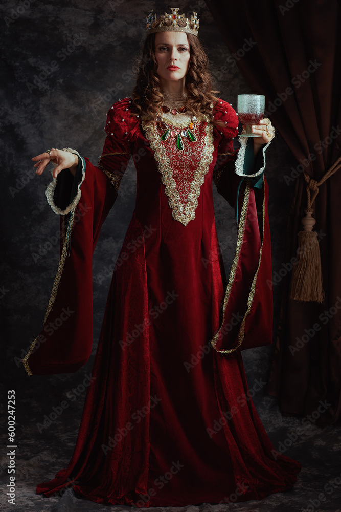 Full length portrait of medieval queen in red dress with goblet