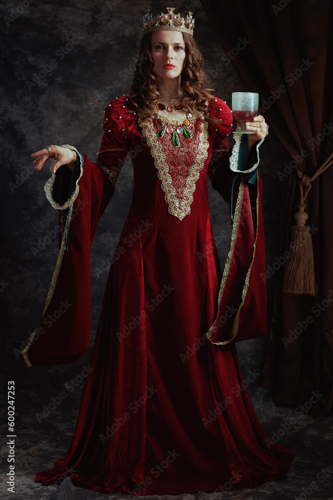 Full length portrait of medieval queen in red dress with goblet Full length portrait of medieval queen in red dress with goblet
