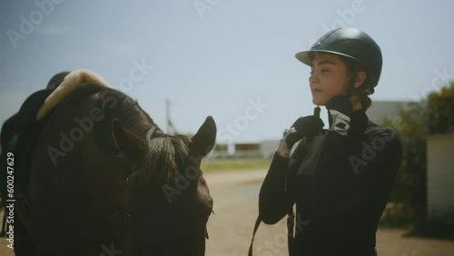 Woman horse rider with horse wearing helmet and petting animal