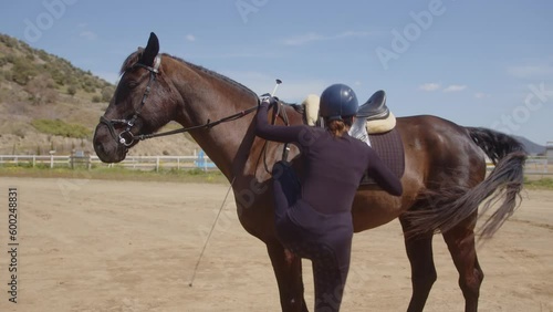 Horse rider mounting and petting happy horse in the countryside
