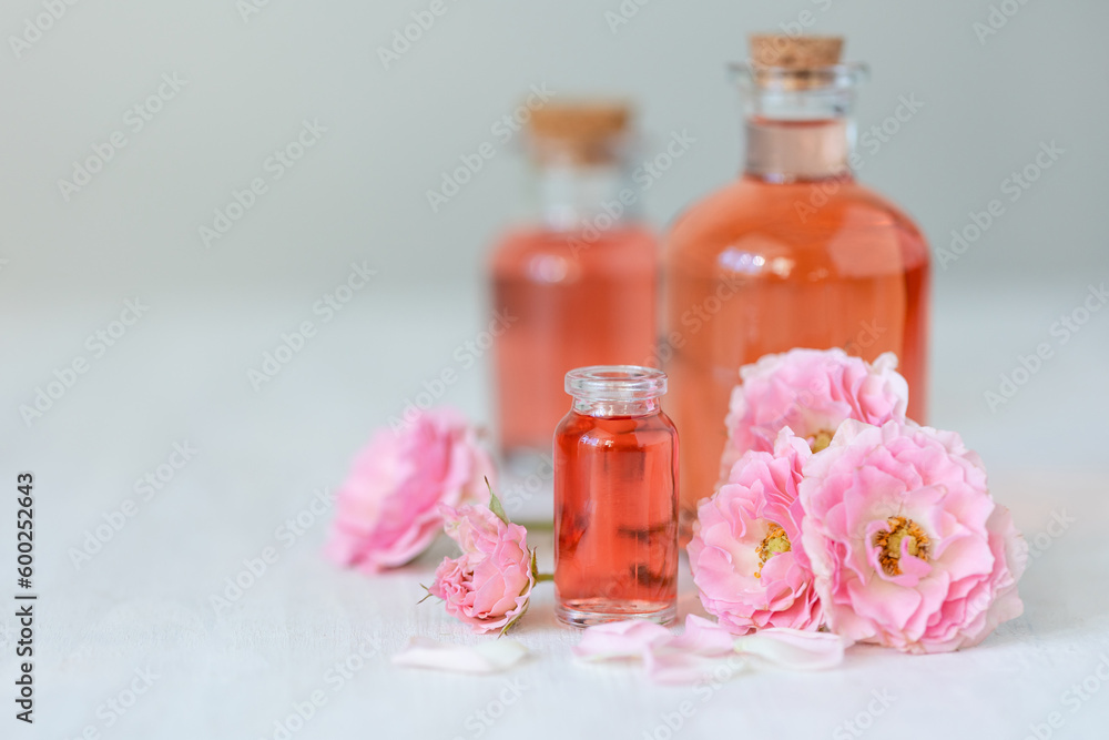 Composition with pure natural organic rose essential oil in glass bottle, luxury perfumery ingredient for premium fragrance, skin care products, anti-age beauty treatment. Fresh flowers Composition with pure natural organic rose essential oil in glass bottle, luxury perfumery ingredient for premium fragrance, skin care products, anti-age beauty treatment. Fresh flowers