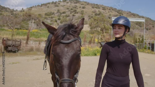 Woman horse rider walking with brown pet horse in nature
